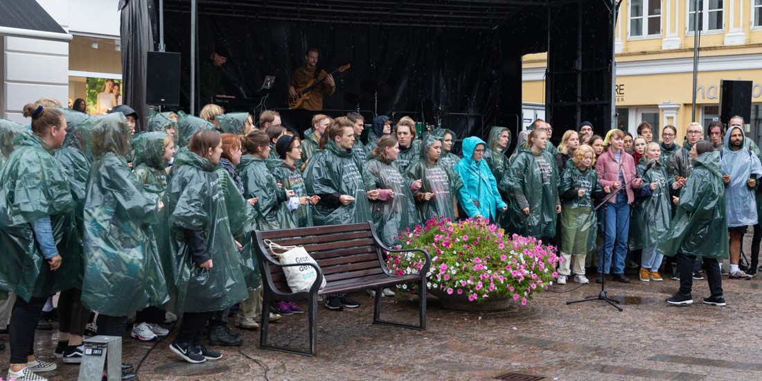 Unge mennesker har regntøj på og synger til en koncert