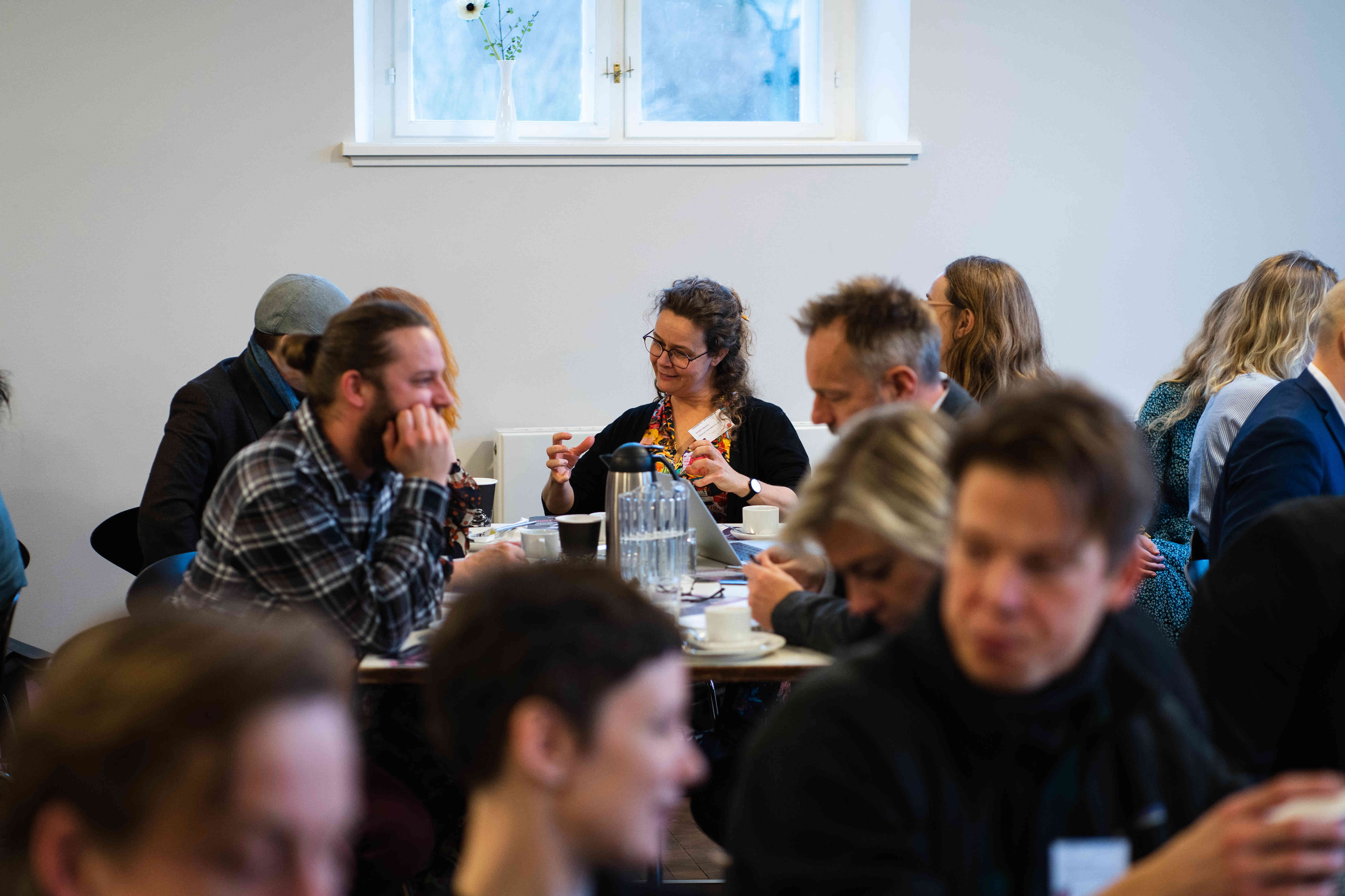Voksne mennesker sidder og arbejder i grupper 