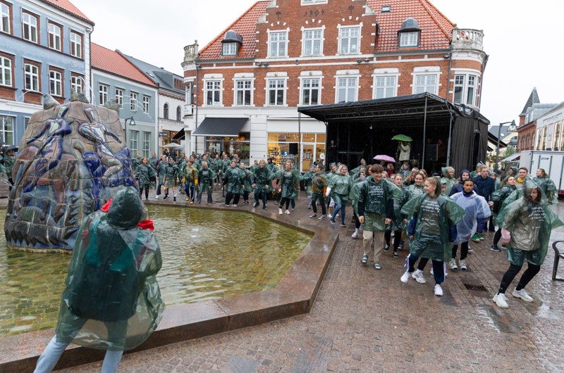 Unge mennesker har regntøj på og er ved et koncerttelt