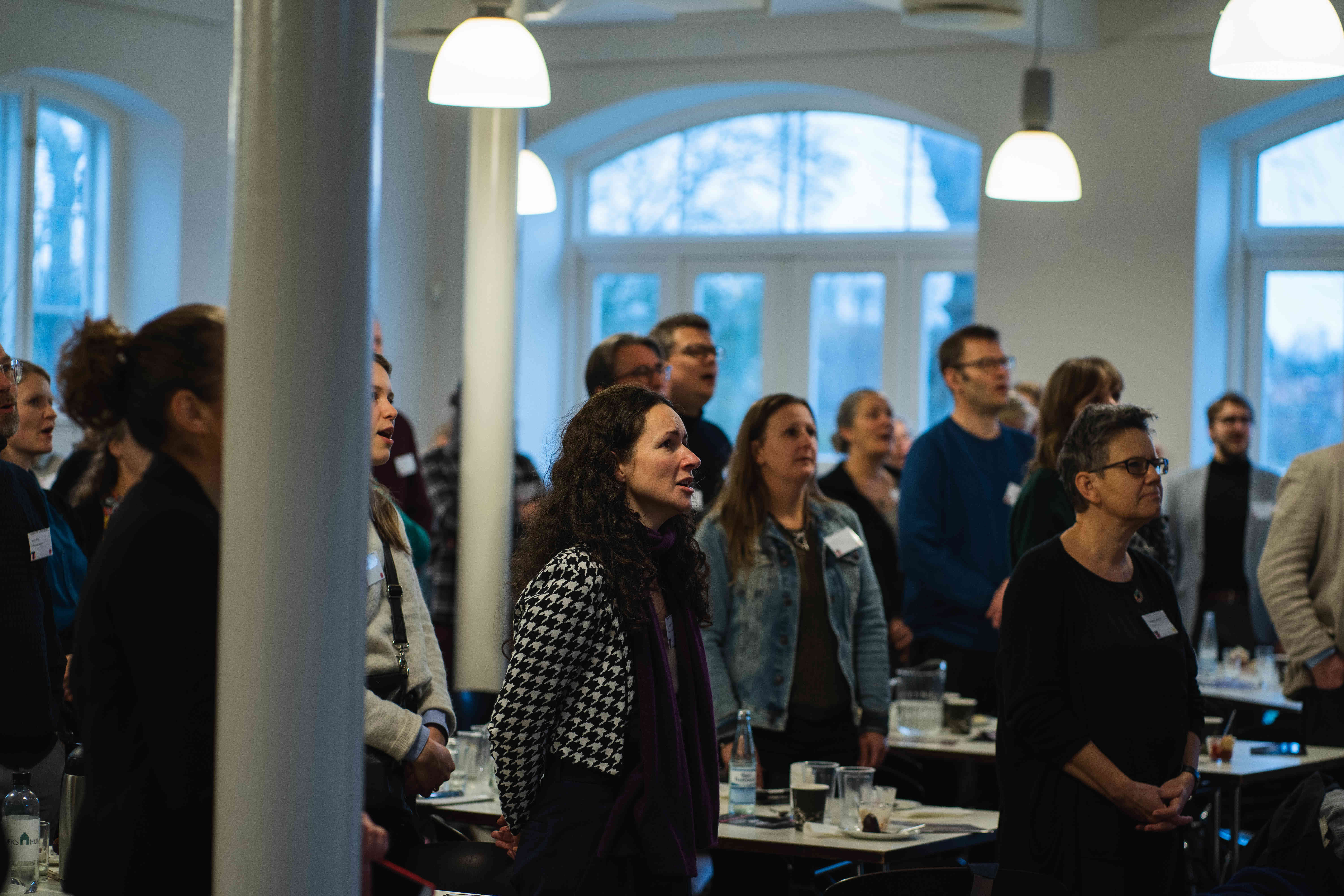 Voksne mennesker står og lytter 