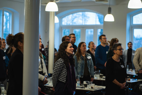Voksne mennesker står og lytter