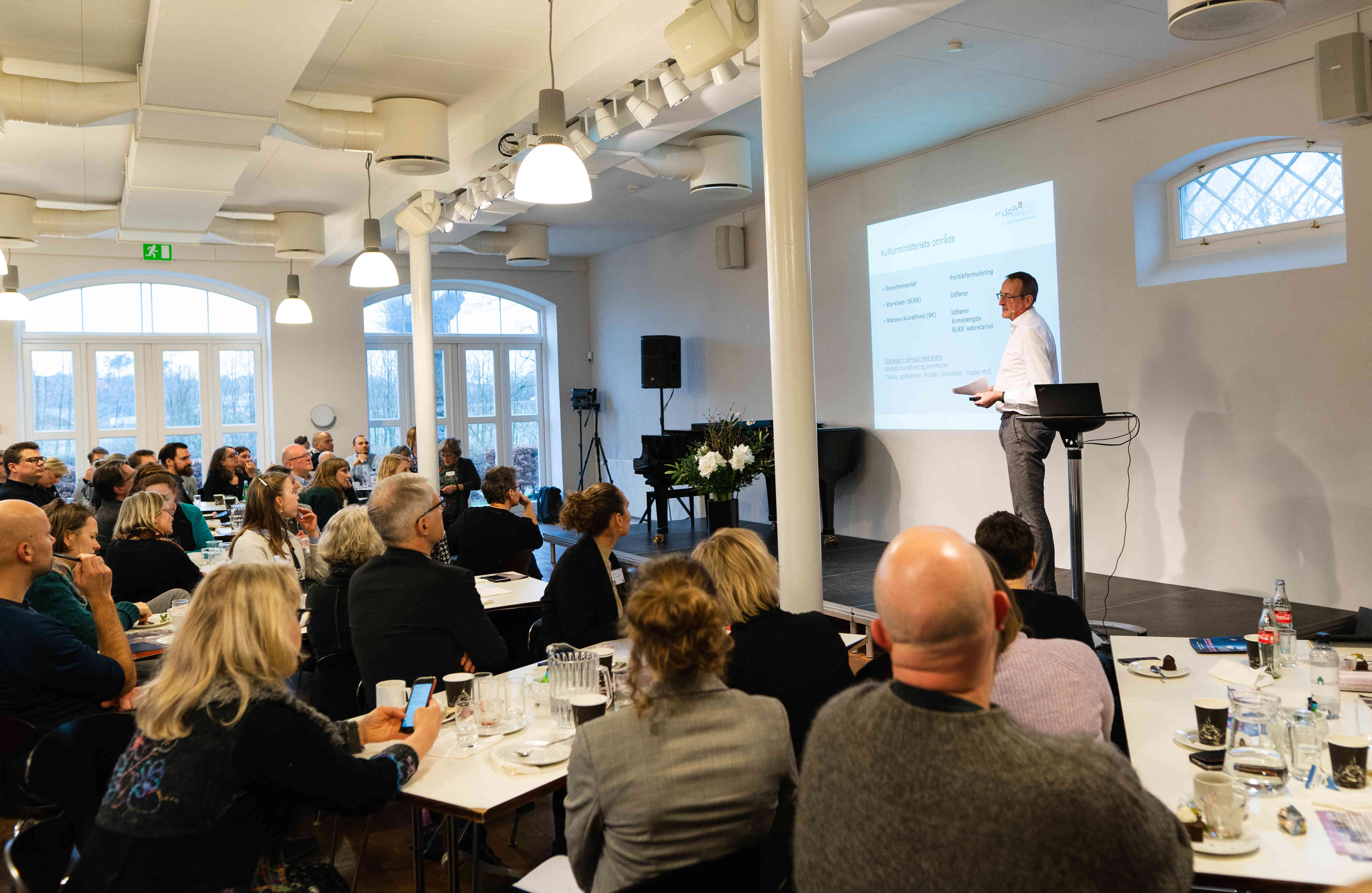 Voksne mennesker sidder og lytter til oplæg 