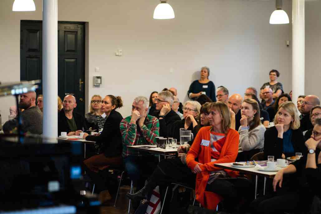 Voksne mennesker sidder og lytter til oplæg 